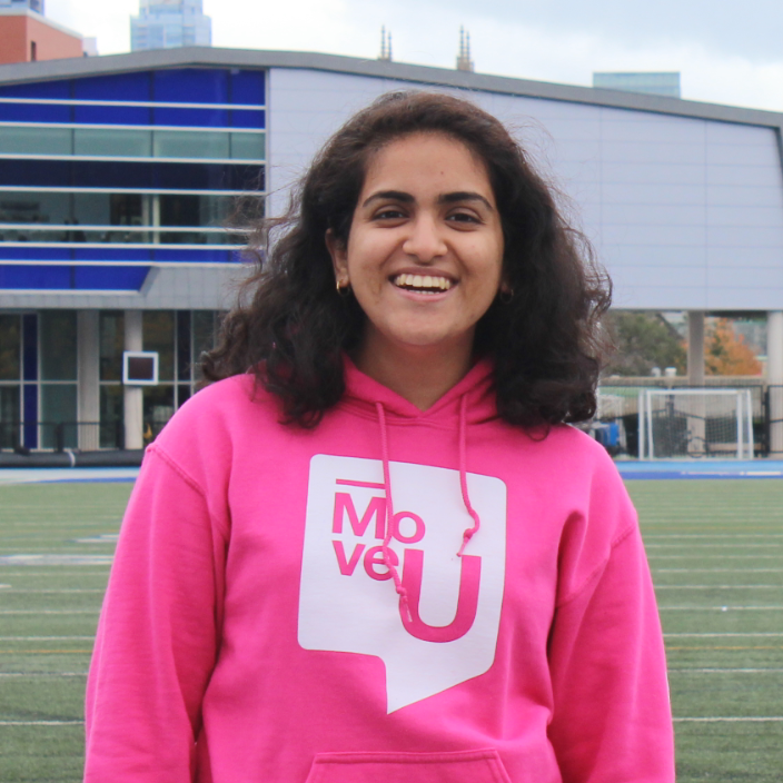 Sukanya Sharma on the athletic field with the CN Tower in the background.